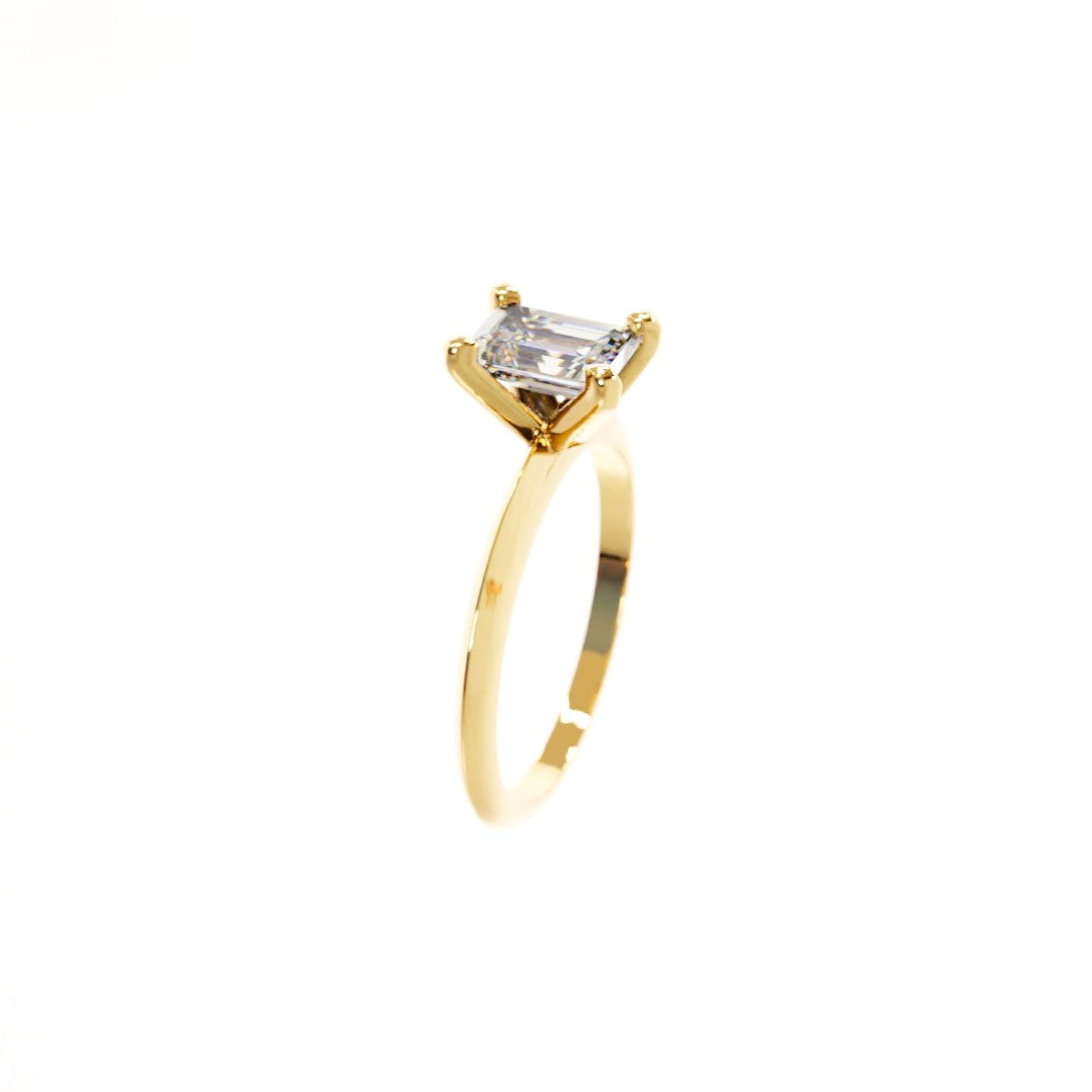 Gold ring with a rectangular diamond on a white background