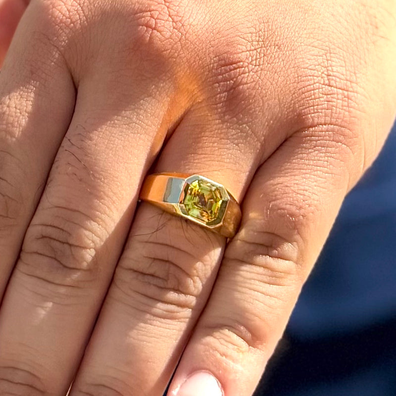 Gold ring with a yellow gemstone on a person's finger