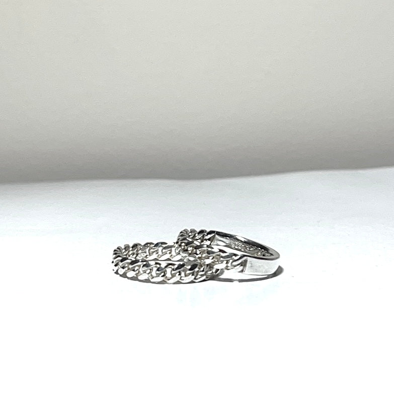 Silver ring with intricate design on a white surface
