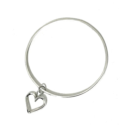 Silver bangle with a heart charm on a white background