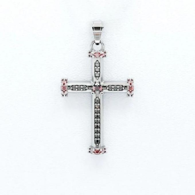 Silver cross pendant with pink gemstones on a white background