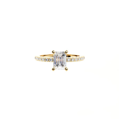 Gold ring with a large diamond and smaller diamonds on the band against a white background