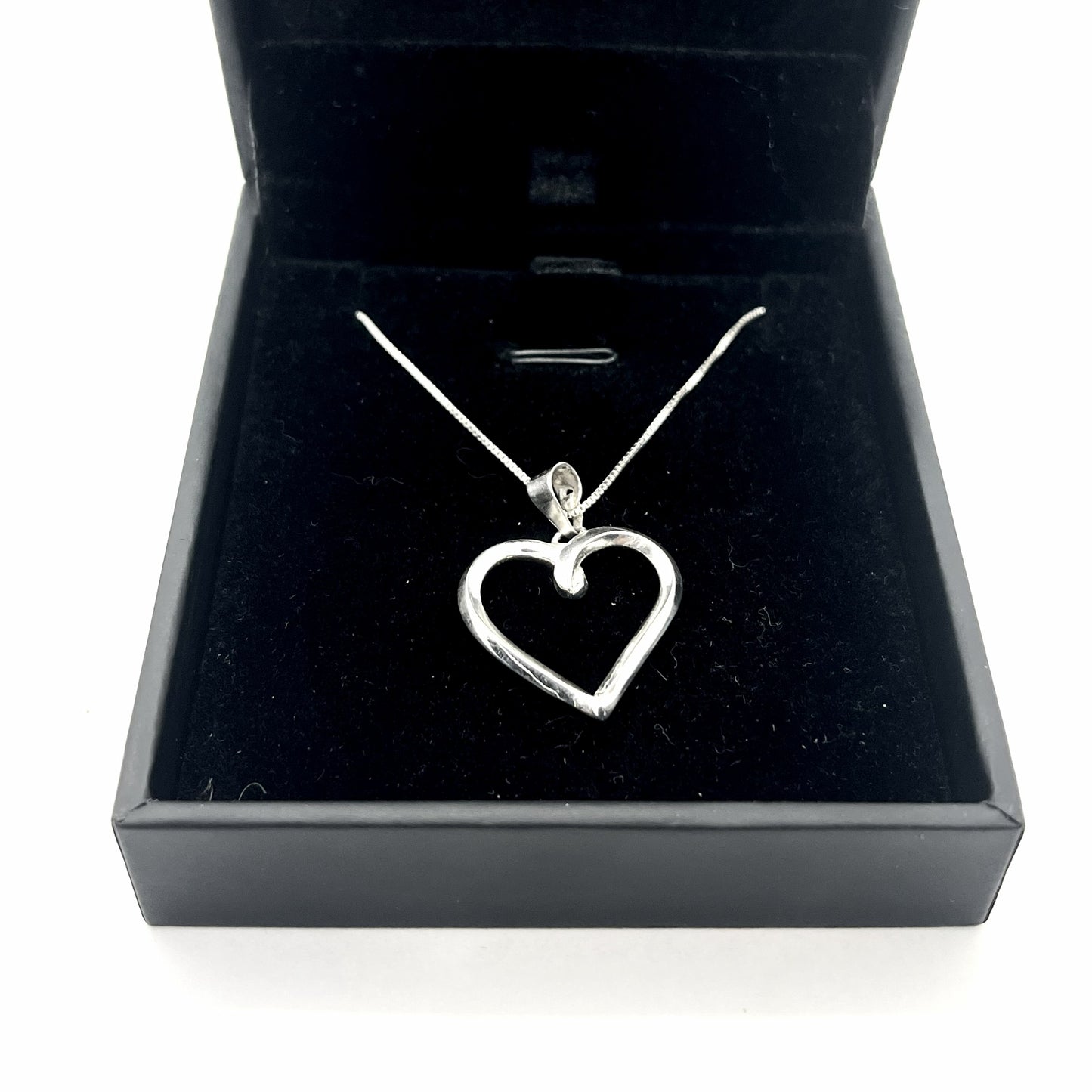 Silver heart-shaped pendant necklace in a black jewelry box
