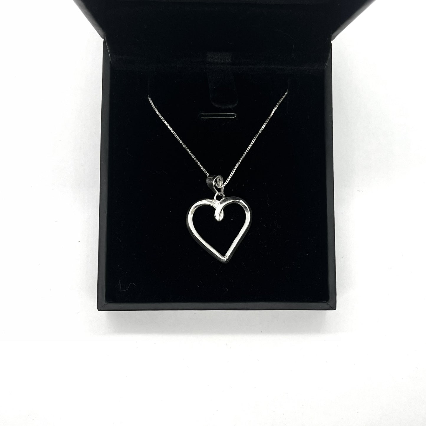 Silver heart-shaped necklace in a black jewelry box on a white background