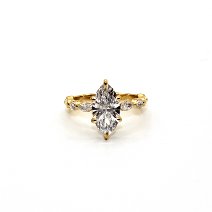 Gold ring with a large diamond and smaller diamonds on the band against a white background