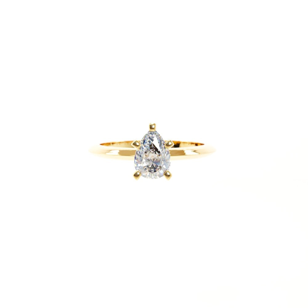 Gold ring with a pear-shaped diamond on a white background