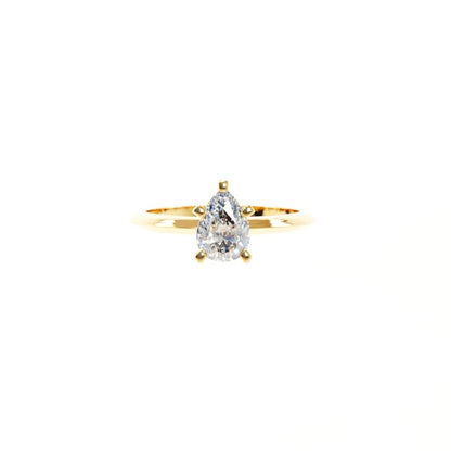 Gold ring with a pear-shaped diamond on a white background