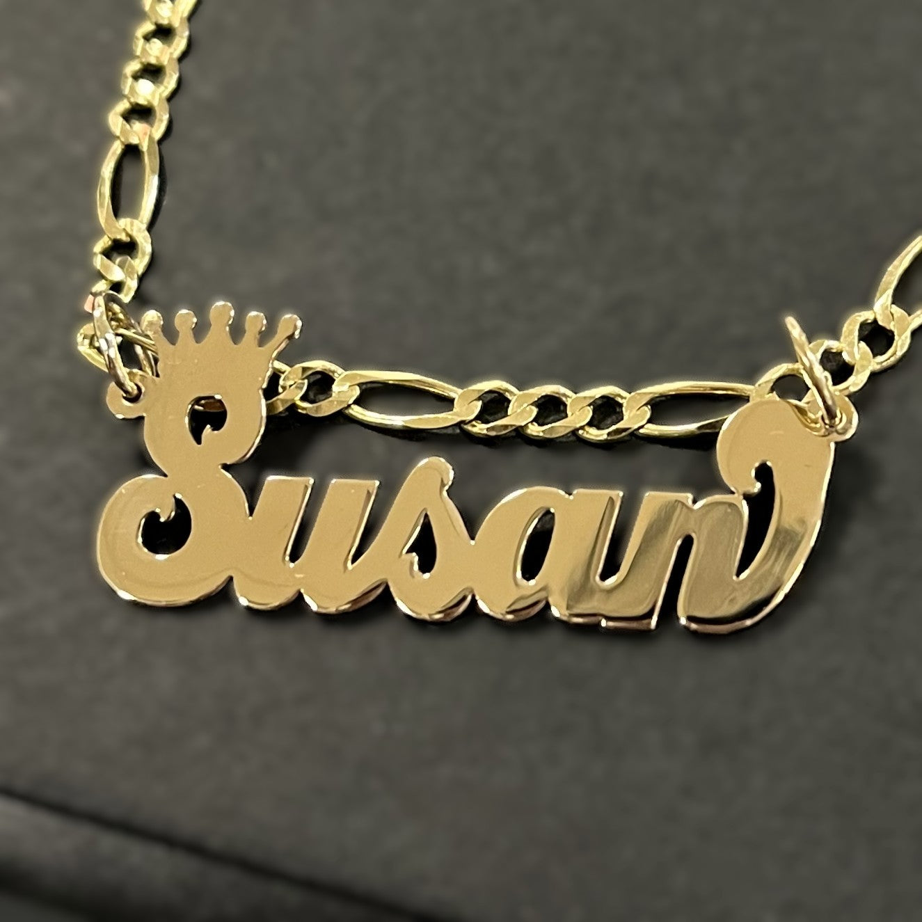 Gold necklace with 'Susan' pendant on a dark background